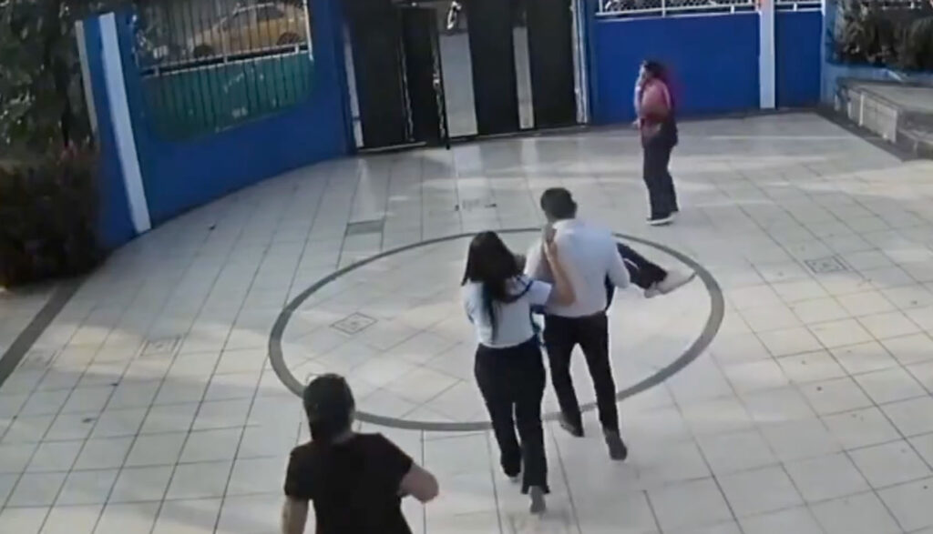 Toma de un video, donde la menor es retirada en brazos por un trabajador del centro educativo.